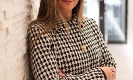 Kendra McKinney, legal professional at Astraea Linskills Solicitors Liverpool, standing with arms crossed against a textured wall.