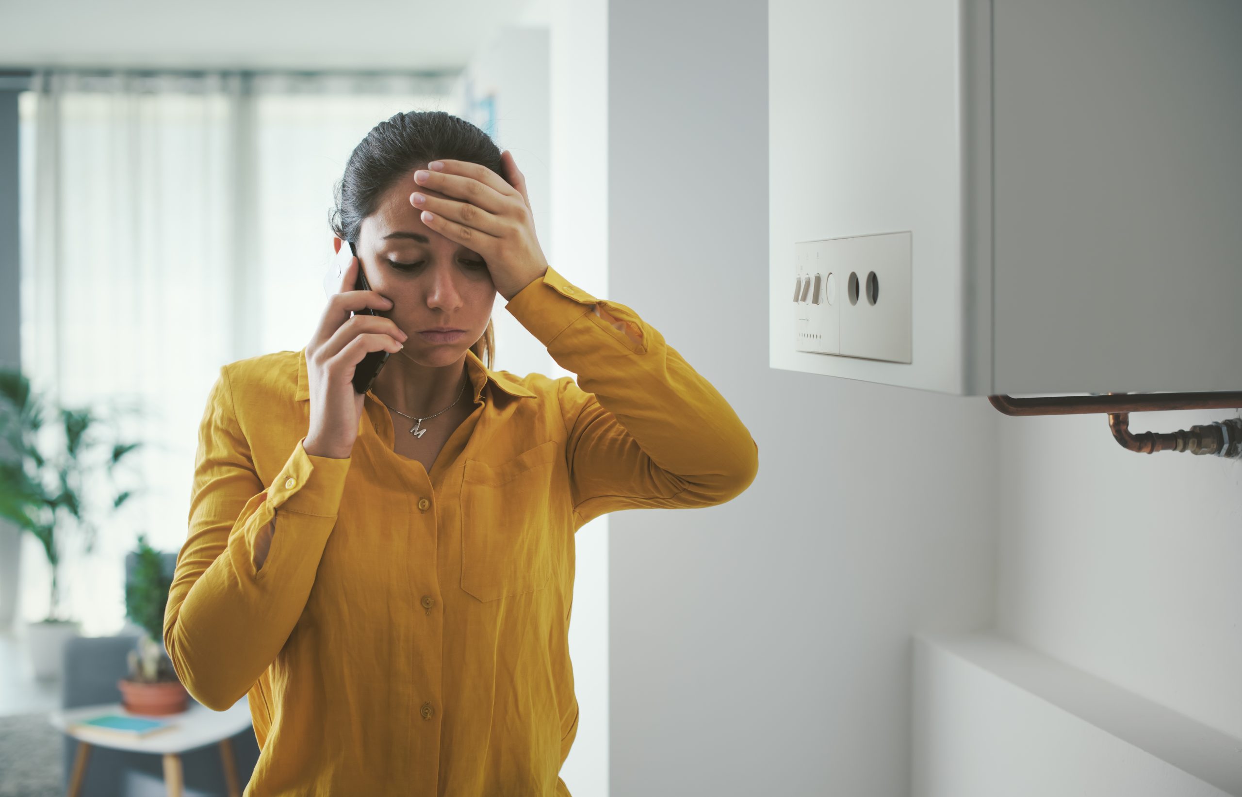 Worried woman making an emergency call for a boiler breakdown service, highlighting housing disrepair issues with legal assistance from Astraea Linskills Solicitors Liverpool.