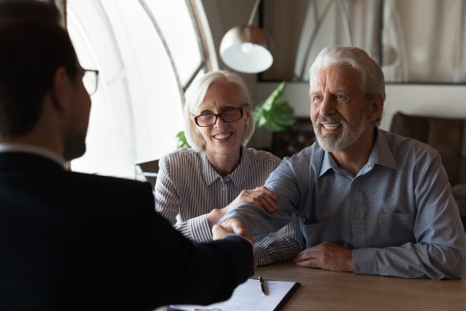 Happy elderly couple shaking hands with a lawyer, symbolizing successful legal guidance on wills and estate planning from Astraea Linskills Solicitors Liverpool.